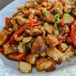 Cashews mixed with Chicken and peppers on a White Plate on the Table