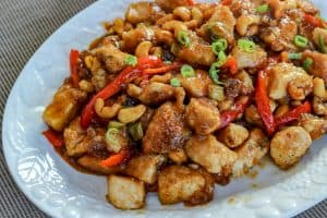 Cashews mixed with Chicken and peppers on a White Plate on the Table