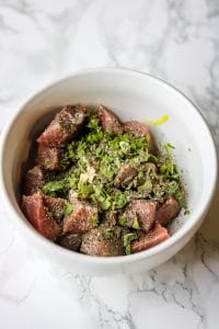 meat in a bowl with seasoning marinating