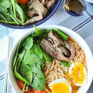 Beef, noodles, spinach, carrots, and soft boiled eggs in broth in white bowl. Full recipe at www.savorythoughts.com