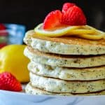 Lemon Poppyseed Pancakes stacked and topped with sliced lemon and strawberries. Serve warm with the syrup or jam of your choice. Perfect for breakfast with a cup of coffee. Lemon Poppyseed Pancakes | Lemon Pancakes | Lemon Pancake Recipes | Poppyseed Pancakes | Pancake Recipes | Breakfast | Breakfast Pancakes | Savory Thoughts #lemonpoppyseedpancakes #poppyseedpancakes #pancakerecipes #breakfastpancakes #breakfast