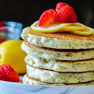 Lemon Poppyseed Pancakes stacked and topped with sliced lemon and strawberries. Serve warm with the syrup or jam of your choice. Perfect for breakfast with a cup of coffee. Lemon Poppyseed Pancakes | Lemon Pancakes | Lemon Pancake Recipes | Poppyseed Pancakes | Pancake Recipes | Breakfast | Breakfast Pancakes | Savory Thoughts #lemonpoppyseedpancakes #poppyseedpancakes #pancakerecipes #breakfastpancakes #breakfast