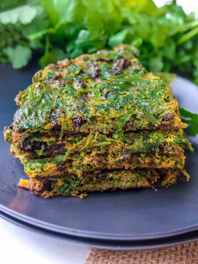 Layered Kuku Sabzi – Persian Herb on a black plate with fresh herbs in the background