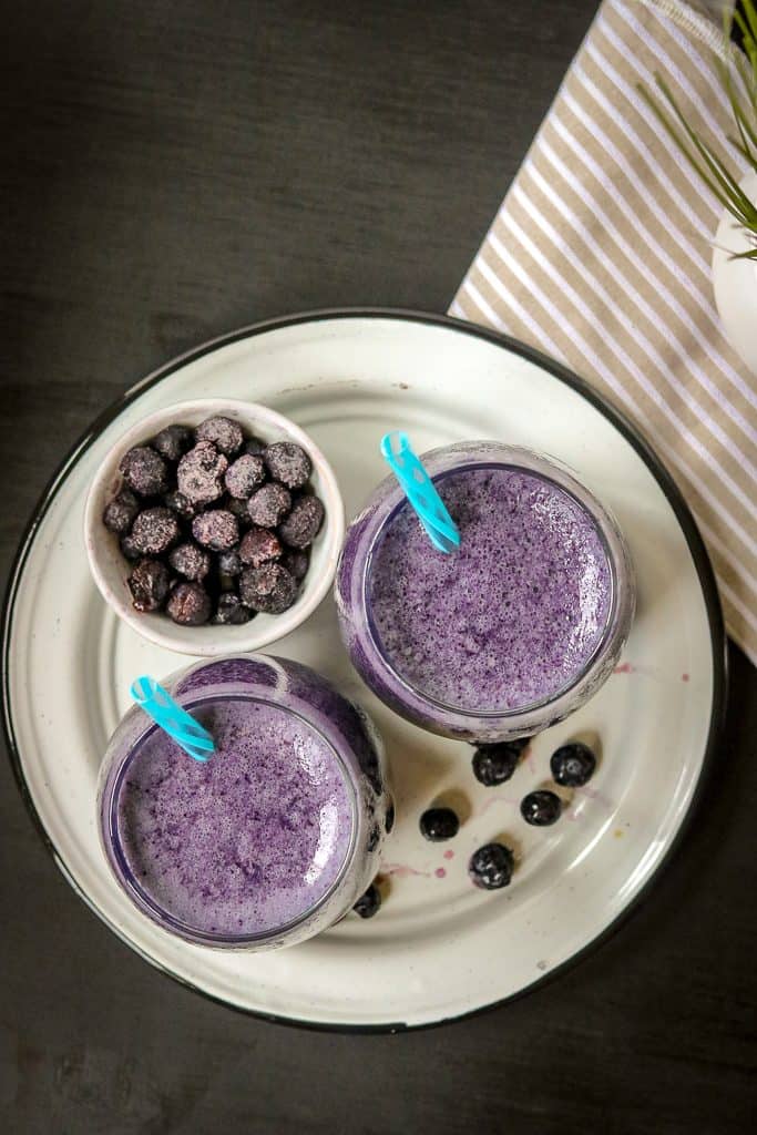 Two glasses of Blueberry Smoothie on a white plate. This Healthy Blueberry Smoothie With Almond Milk makes an easy breakfast or snack for adults and children.