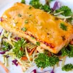 Honey Mustard Glazed Salmon on top of vegetable bed served on a white plate. Honey Mustard Glazed Salmon - Air Fryer Recipe is a quick, easy, and a healthy weeknight dinner. A hearty baked salmon recipe that’s fuss-free! Baked salmon fillet made in the air fryer to perfection. A flavorful simple meal that that’s ready in 10 minutes. #air fryer #honey #mustard #dijonmustard #recipes #paleo #honeymustardglaze #healthy #lemon