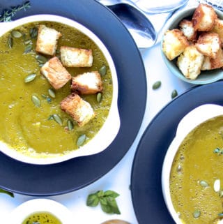 two bowls of squash soup topped with toasted bread and pumpkin seeds