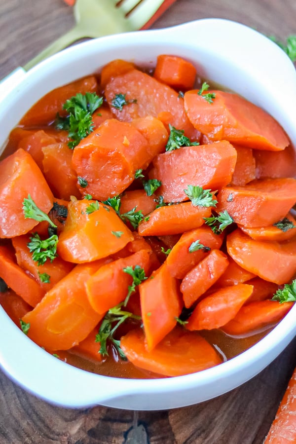 Easy glazed carrots in white bowl topped with fresh parsley