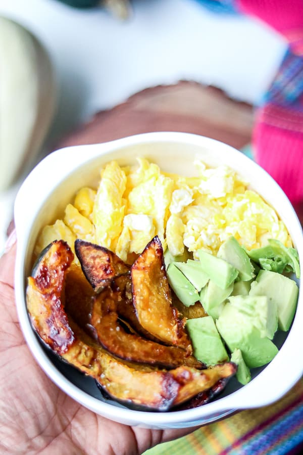 roasted squash with eggs and avocados in a white bowl. 