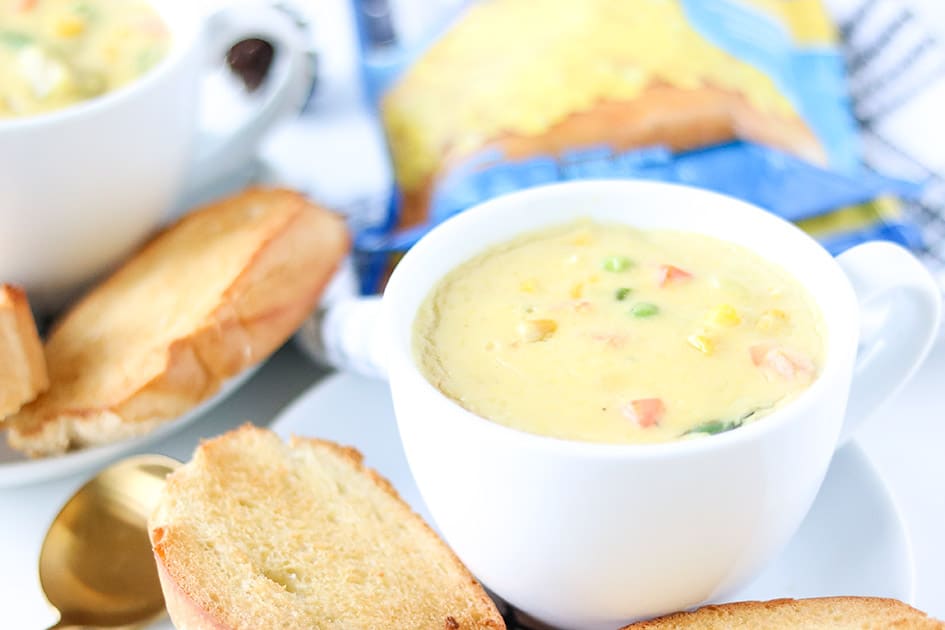 Vegetarian corn chowder in white cup with bread