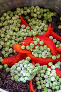 frozen peas and red bell peppers in Haitian black rice