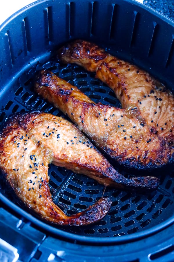 salmon steaks in air fryer basket topped with black sesame seeds