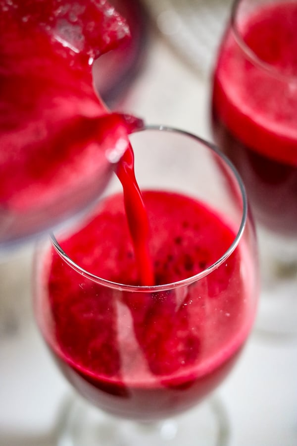 Beets carrots apple juice in vitamix blender being poured in glass