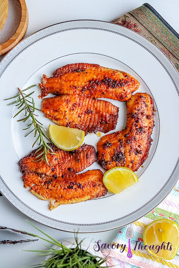 3 pieces of blackened tilapia fish with 2 slices of lemon and rosemary