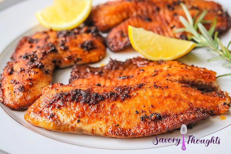 Cajun Fish with lemon and rosemary on white plate