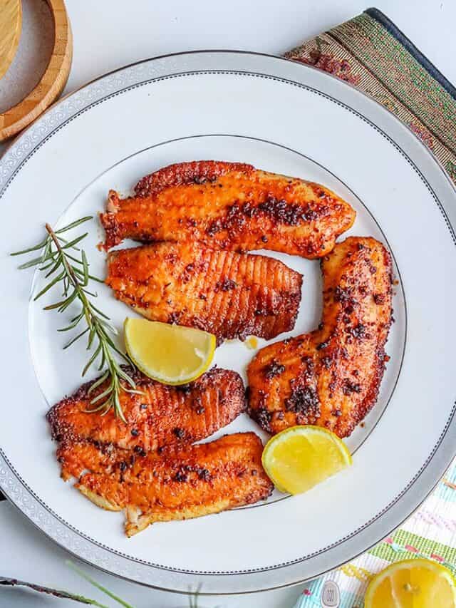 3 pieces of blackened tilapia fish with 2 slices of lemon and rosemary