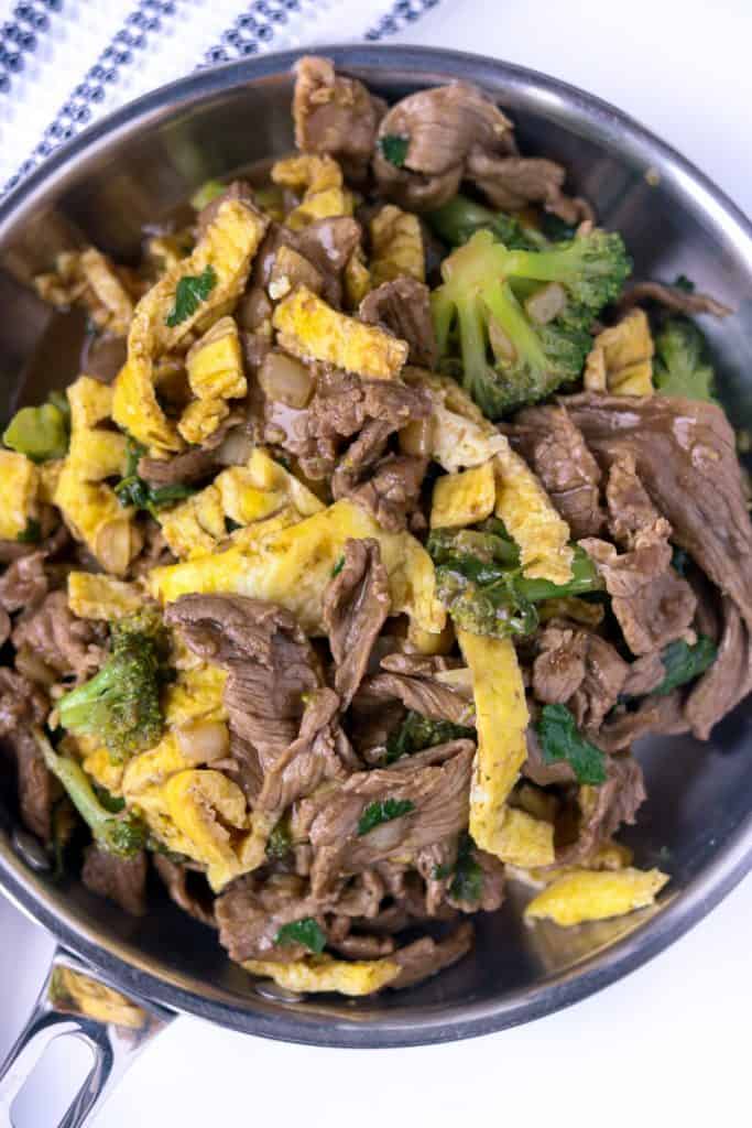 Cooked beef with eggs and broccoli in skillet