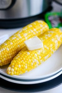 Corn on white plate with butter on top