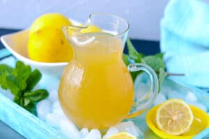 Lemonade in pitcher over ice on a blue tray