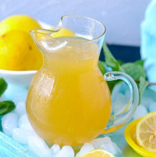 Lemonade in pitcher over ice on a blue tray