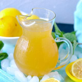 Lemonade in pitcher over ice on a blue tray