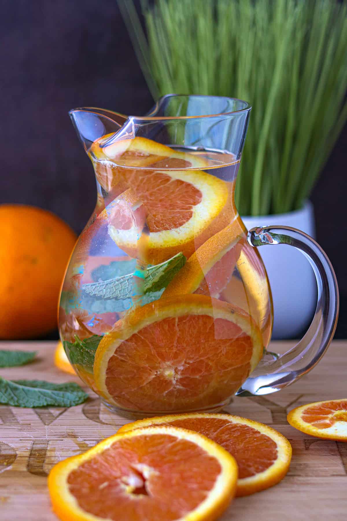 Orange Infused Water In pitcher with orange slices on cutting board