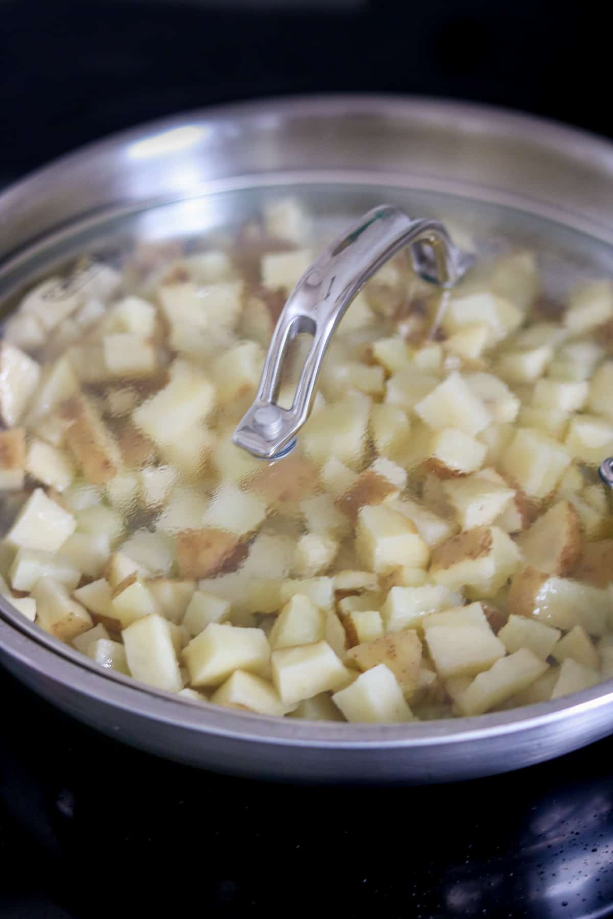 Potatoes covered in skillet cooking