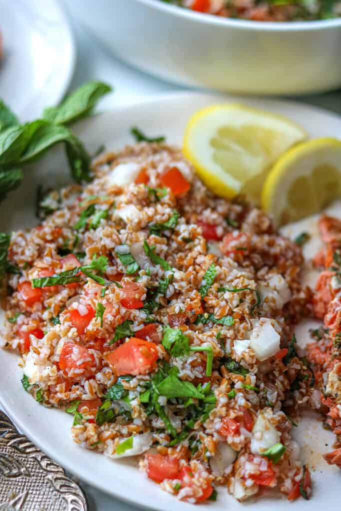 Bulgar salad on white plate with lemon wedges