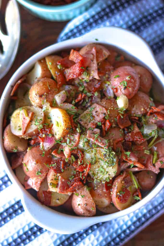 potato salad on a wooden cutting board topped with herbs