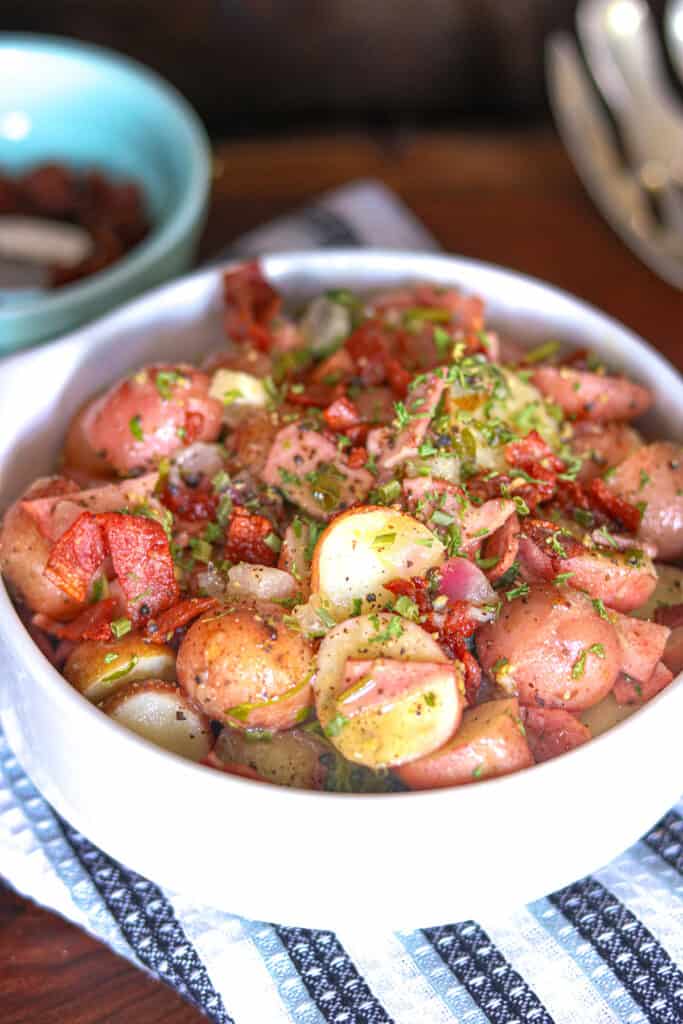 hot potato salad in white plate topped with fresh parsley