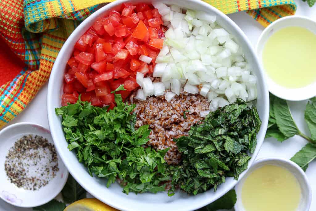 Tomatoes, onions, mint, bulgur, parsley in large bowl 