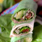 Tuna Wraps stacked on top of each other on a bed of spinach leaves