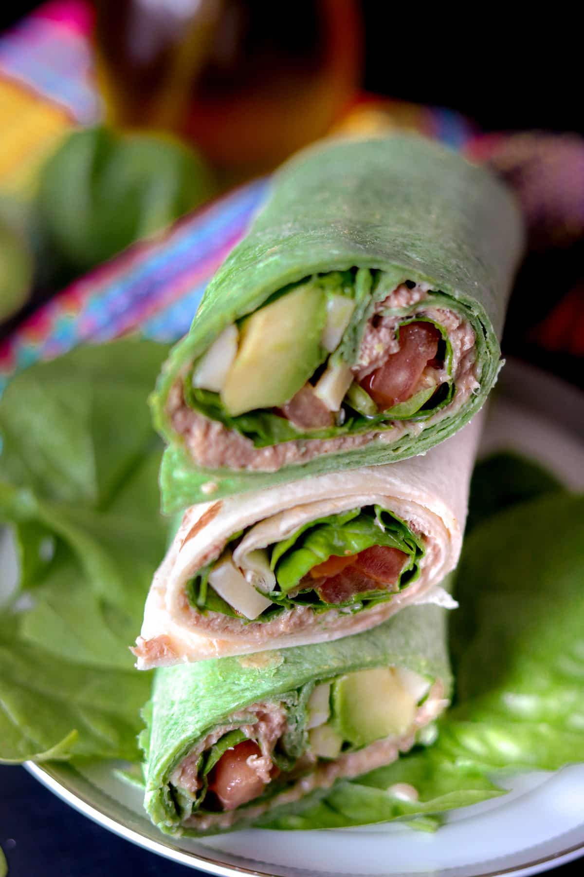 Tuna Wraps stacked on top of each other on a bed of spinach leaves