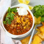 Turkey taco soup in white plate topped with fresh herbs and sour cream