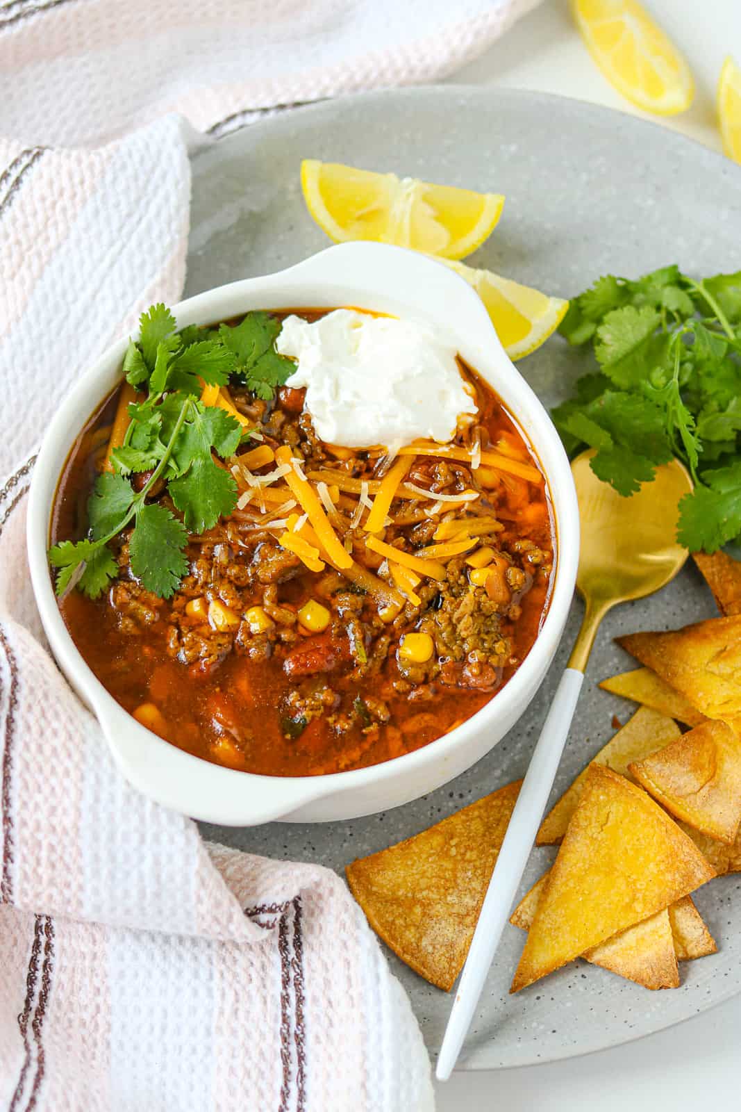 Turkey taco soup in white plate topped with fresh herbs and sour cream