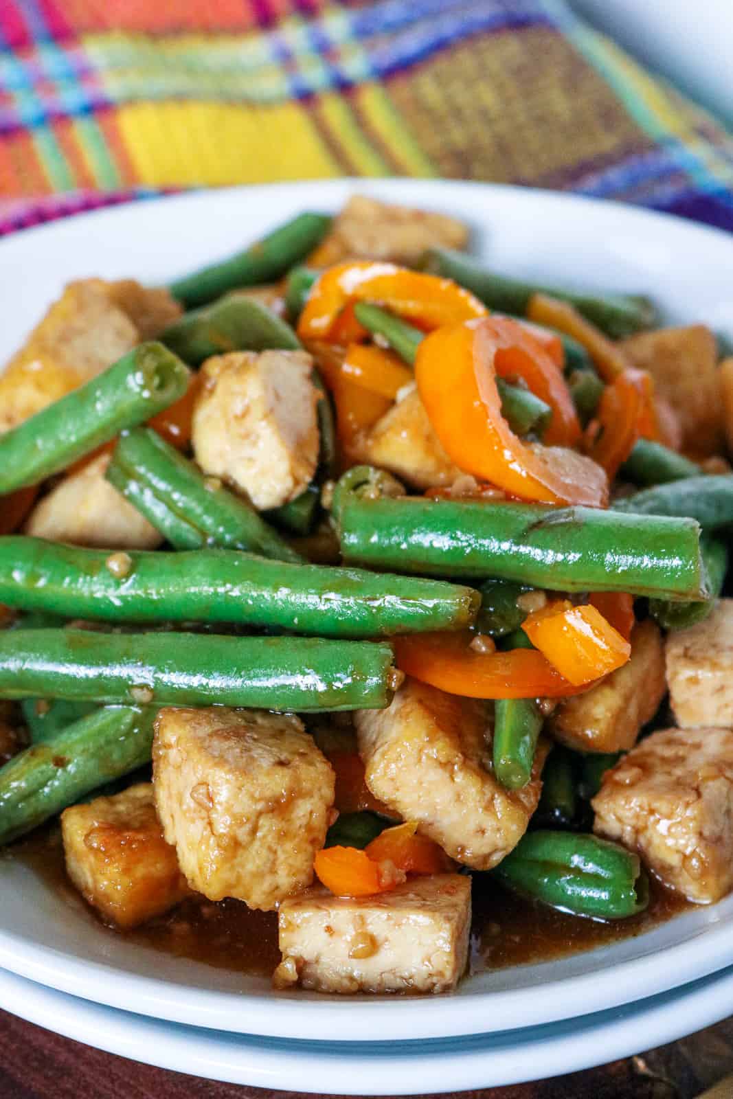 Tofu and green beans with peppers on a white plate