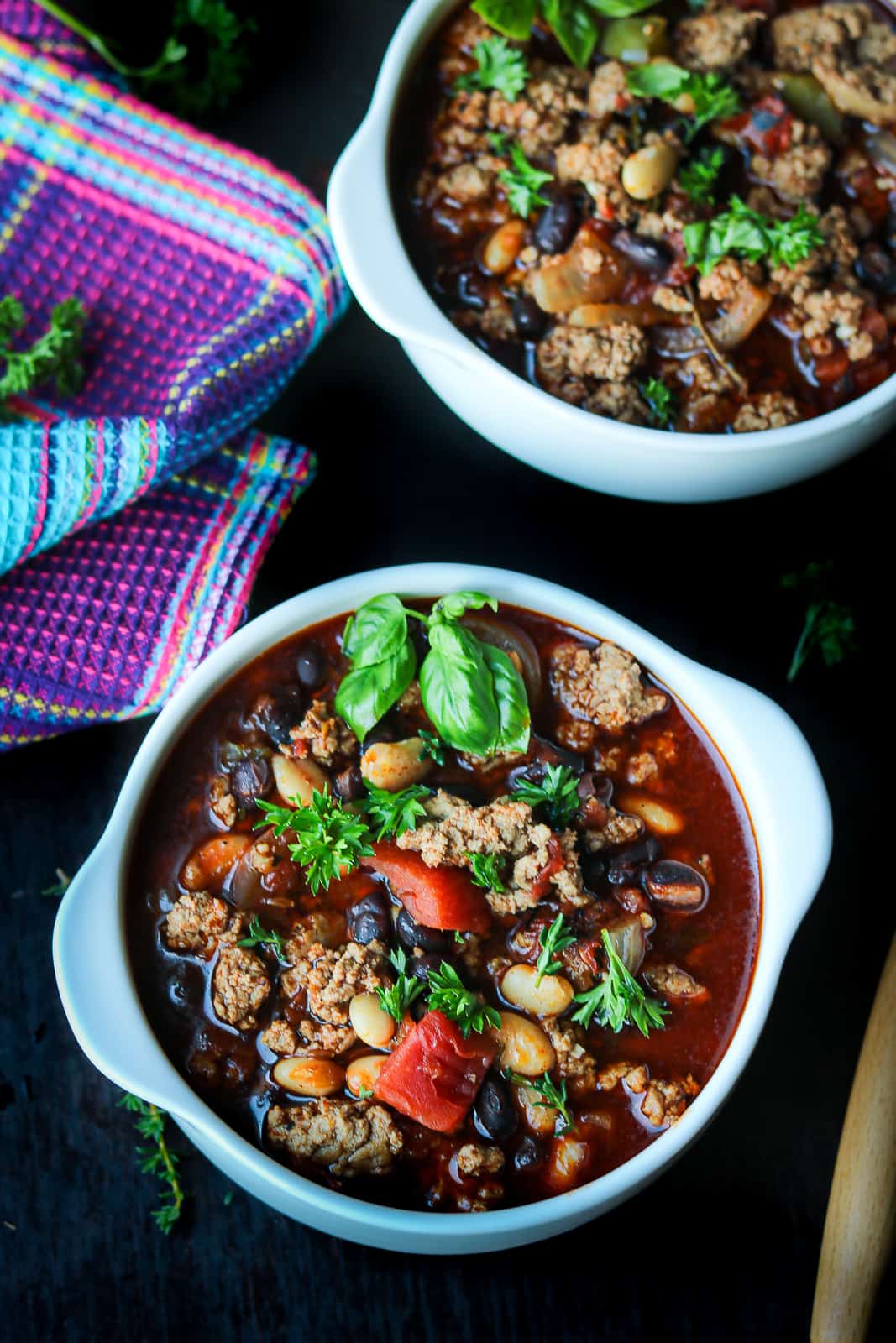 bean soup with turkey meat and fresh herbs in white bowl