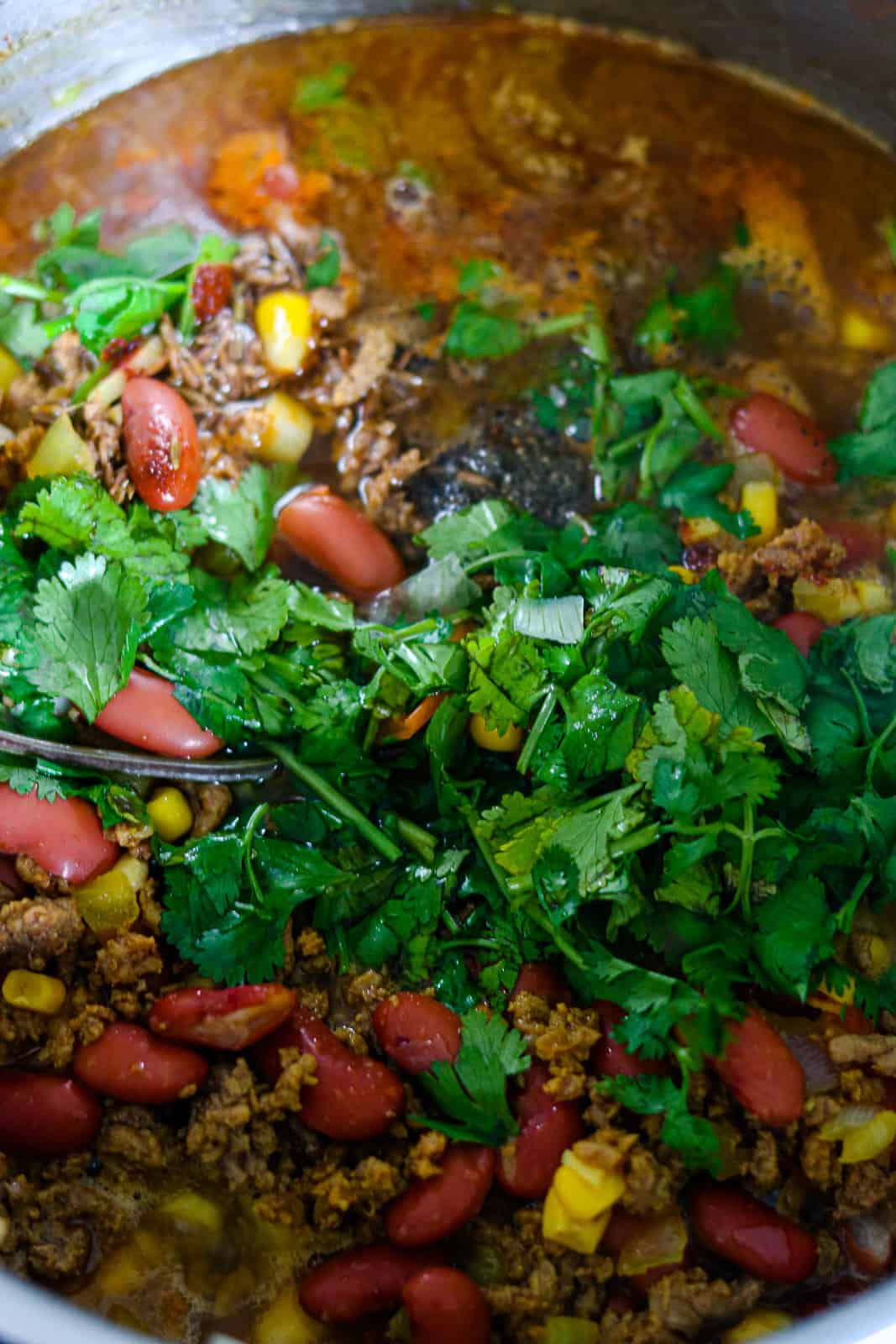 cilantro on top of beans, meat and corn in pot