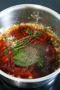 herbs, salt and pepper, Ketchup, molasses in sauce pan with garlic and onions