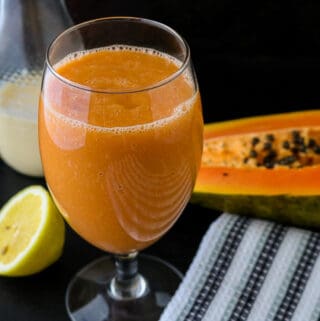 Papaya Juice in glass on blackboard with lemon and papaya in the background with almond milk