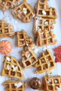 Waffle pieces on white background with walnuts on top with syrup.