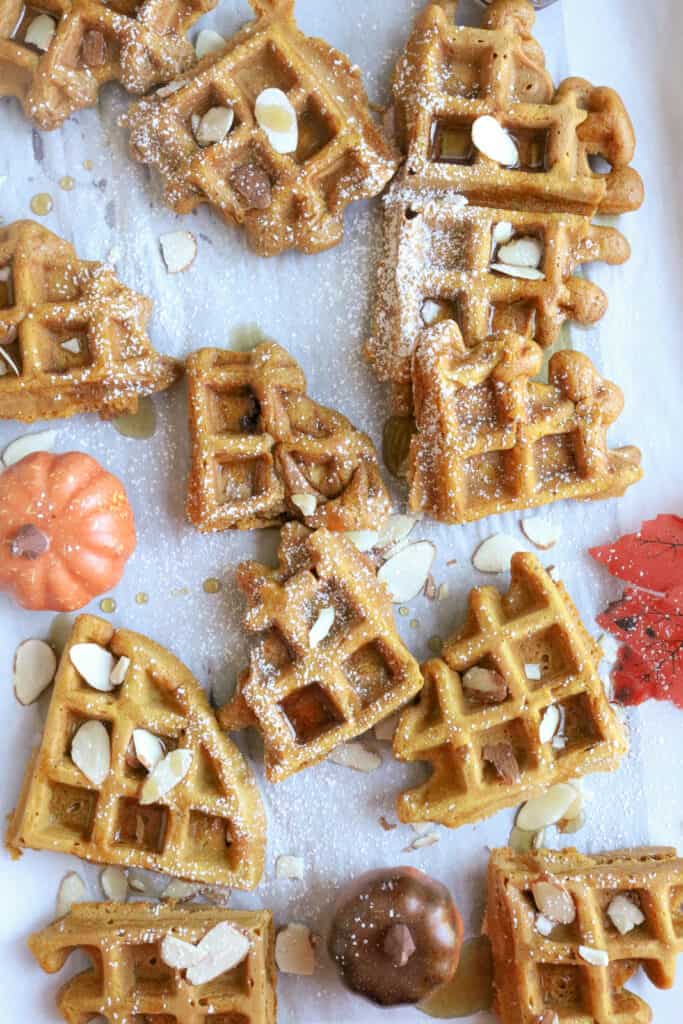 Waffle pieces on white background with walnuts on top with syrup. 