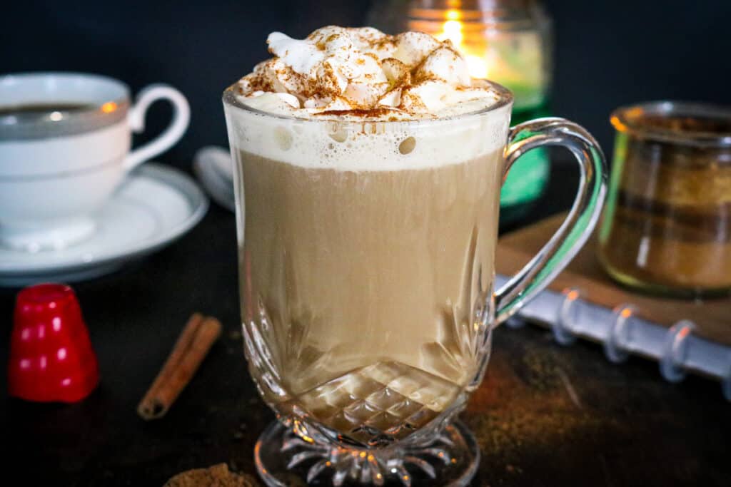 latte in clear mug topped with whipped cream and cinnamon