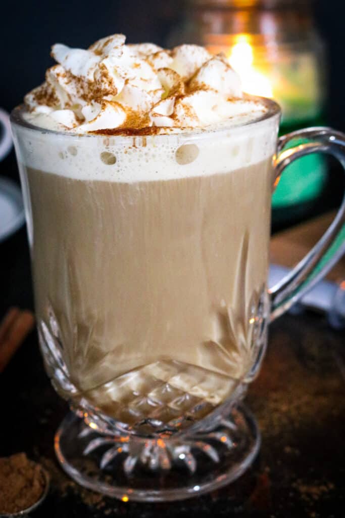 PUMPKIN LATTE IN CLEAR MUG TOPPED WITH WHIPPED CREAM AND CINNAMON