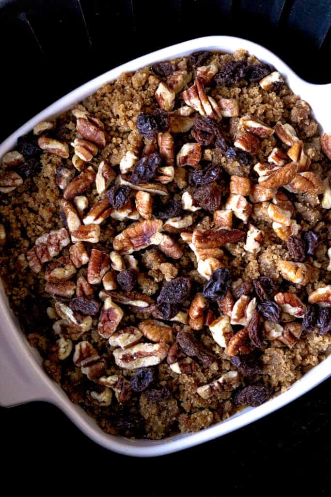 sweet potato topped with pecans and raisins in white dish