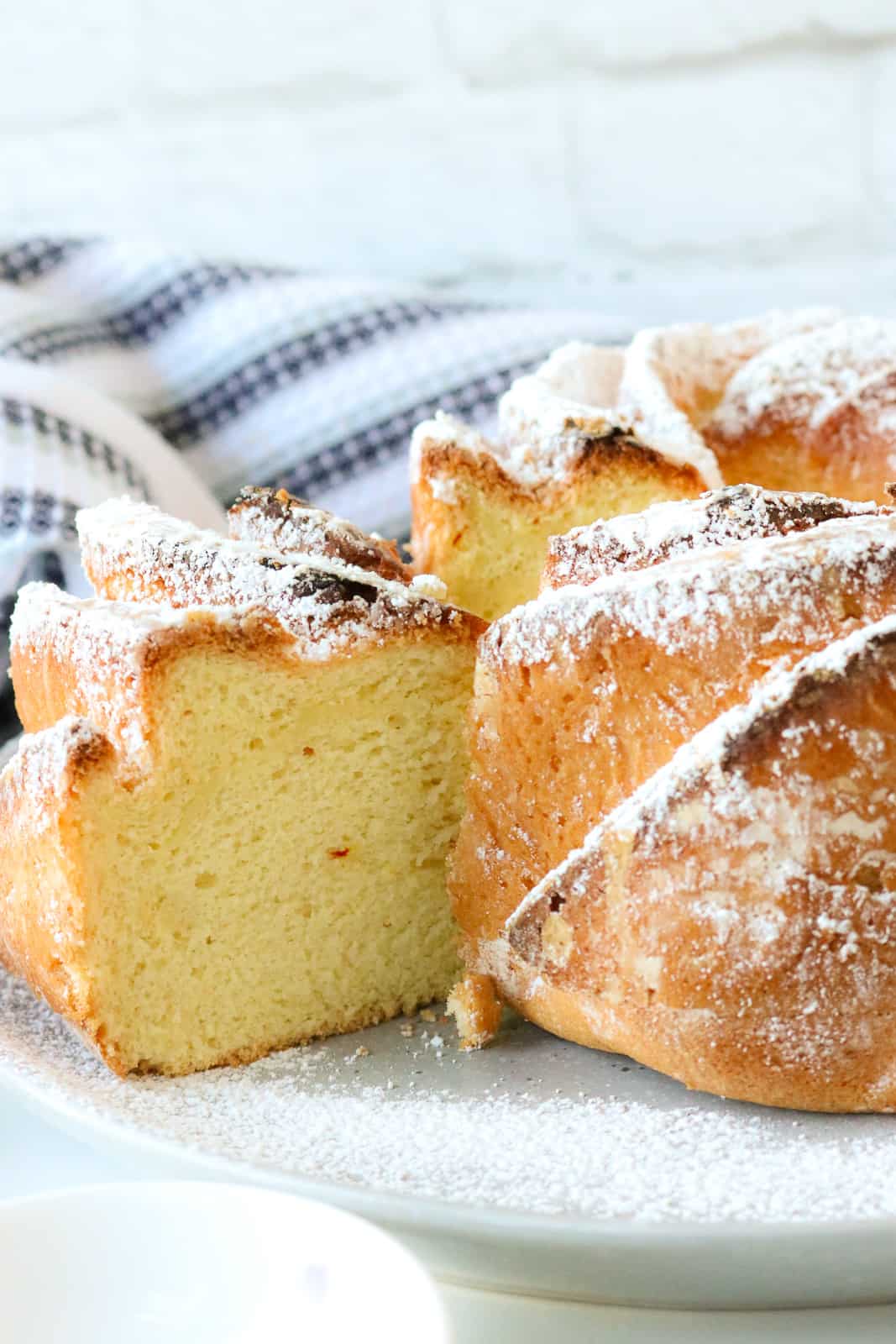 Saffron cake with slice cut out on a plate topped with powdered sugar