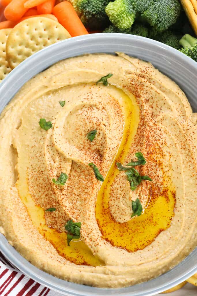 hummus in gray bowl topped with herbs and olive oil