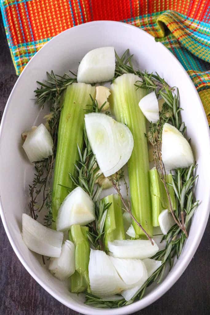 Onions, celery and herbs in a baking dish.