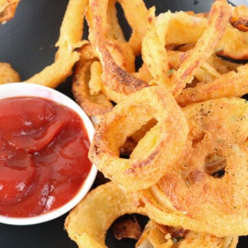 Onion Rings on black plate with ketchup