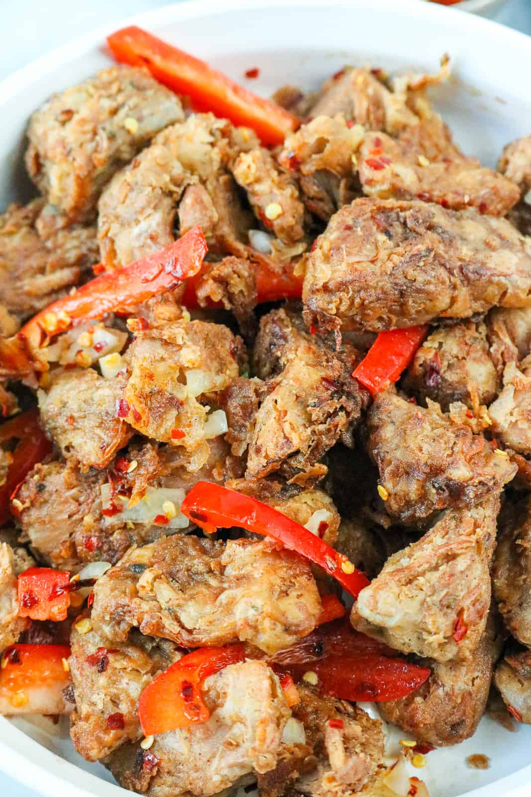 Close up picture of fried vegan pork, jackfruit, griot topped with red bell pepper slices