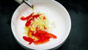 oil dripping on peppers and onions in white plate